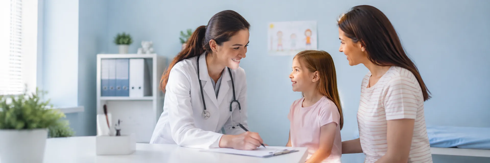 Pediatrician warmly interacting with a child and parent in a bright exam room